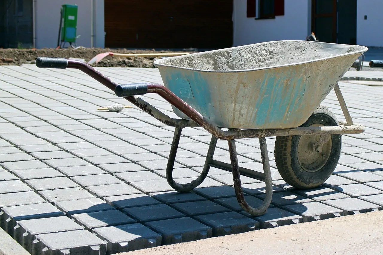 A builder's wheelbarrow standing on newly laid grey concrete pavers on a building site